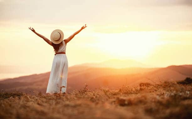 Happy woman standing with her back on the sunset in nature in summer. How To Reclaim Your Life’s Happiness By Demolishing The #1 Self-Esteem Killer