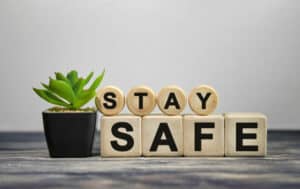 STAY SAFE - text on wooden cubes, green plant in black pot on a wooden background. For herbs for anxiety and depression. 