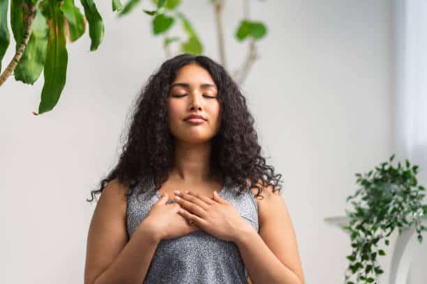 A beautiful and young multiracial woman is doing breathing exercise at home. Emotions of Faithfulness