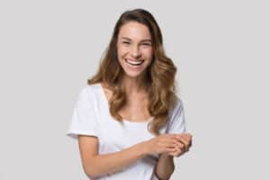 Laughing millennial woman posing over white wall bac