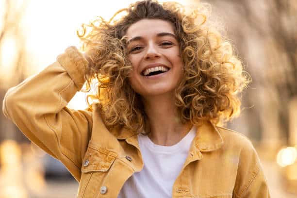 Portrait of young woman with curly hair in the city. The ultimate self-esteem.