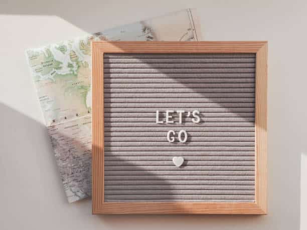 Letter board with words LET'S GO and touristic map of USA. Top view on flat lay board with heart, symbol of love to travel. Wanderlust background with sunlight and shadow. Happiness's Road Map
