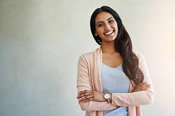 A studio photograph captures a confident and joyful young woman confidently crossing her arms. Discover 7 unexpectedly rapid and simple techniques to enhance your happiness.