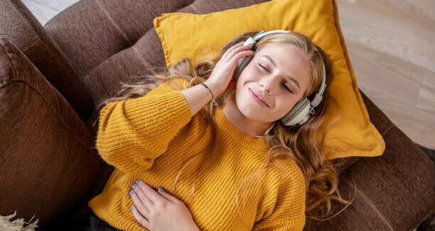 Woman in tune with who she is listening to music on the couch 