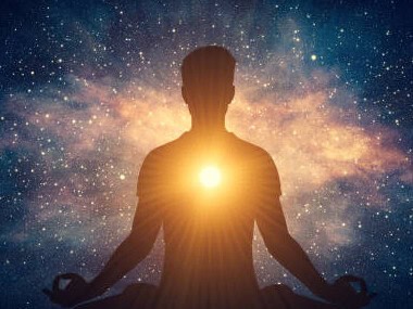 Silhouette of a person meditating in lotus position with a glowing light at their heart, set against a cosmic galaxy background.